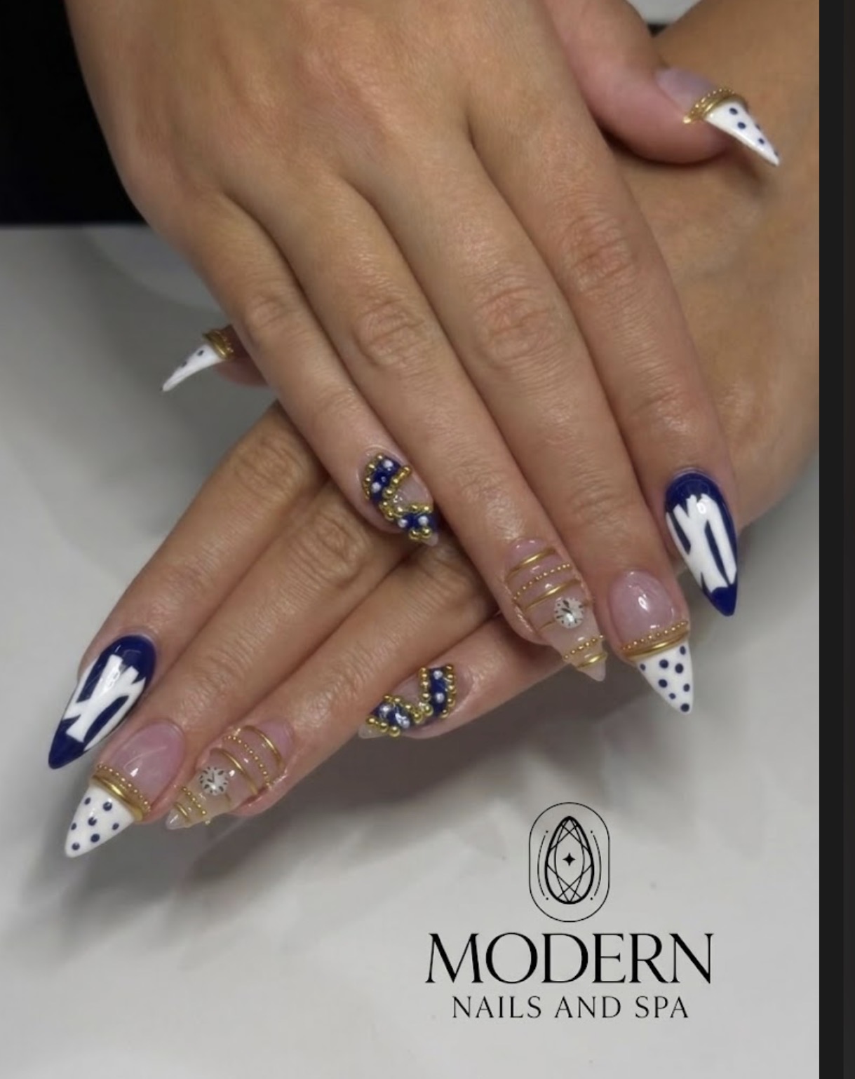 Navy and white stiletto nails with gold bead detailing
